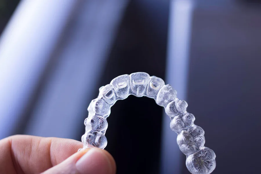 A clear Forgiver retainer held between two fingers